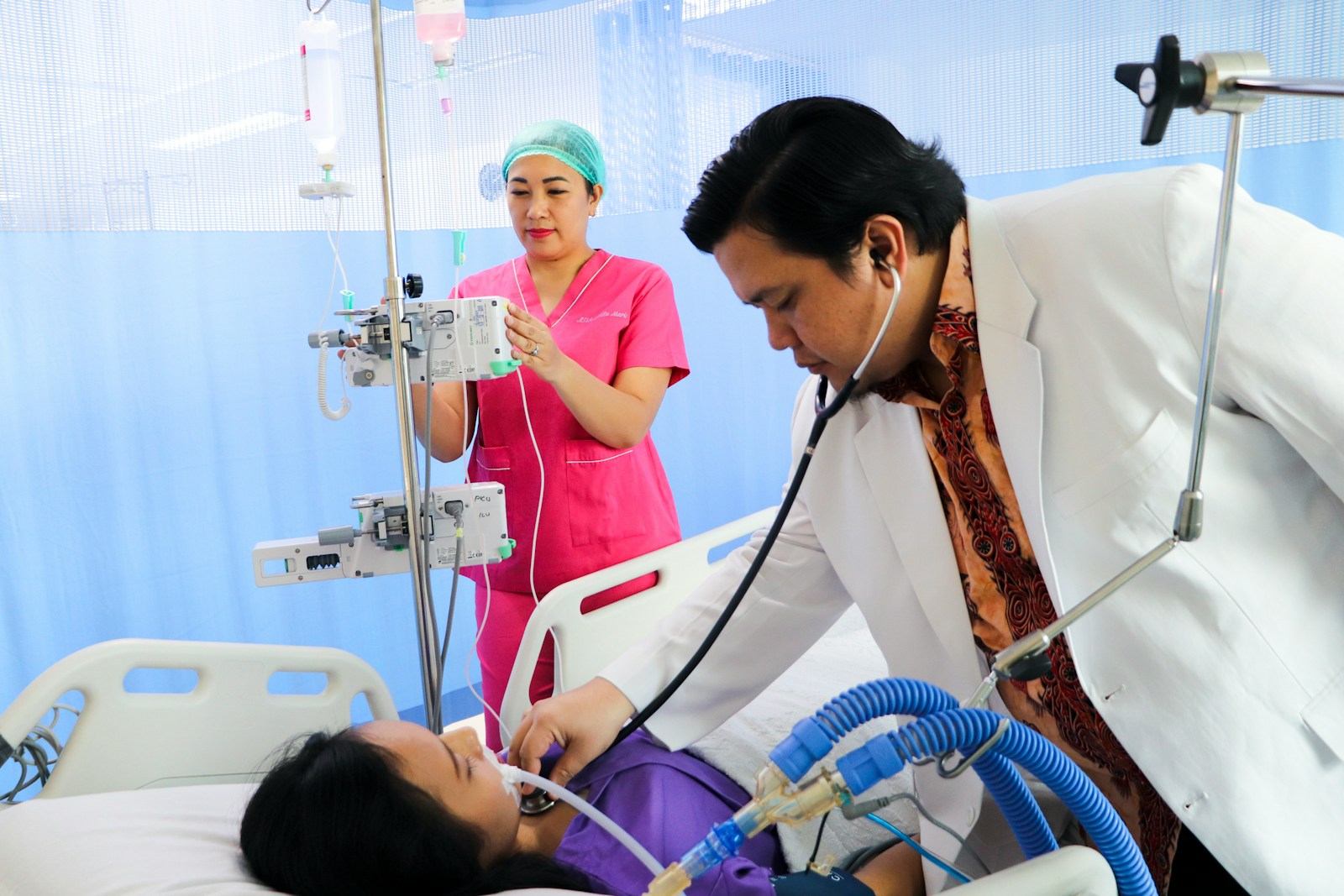 a man laying in a hospital bed being examined by a nurse